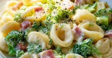 Teller mit Brokkoli Schinken Pasta, dekoriert mit frischen Kräutern