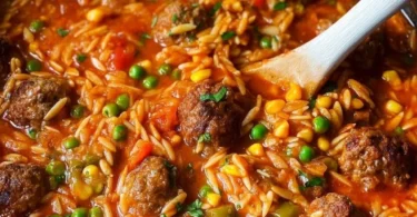 Bunte Orzo-Pfanne mit Hackbällchen in einem dekorativen Teller serviert.